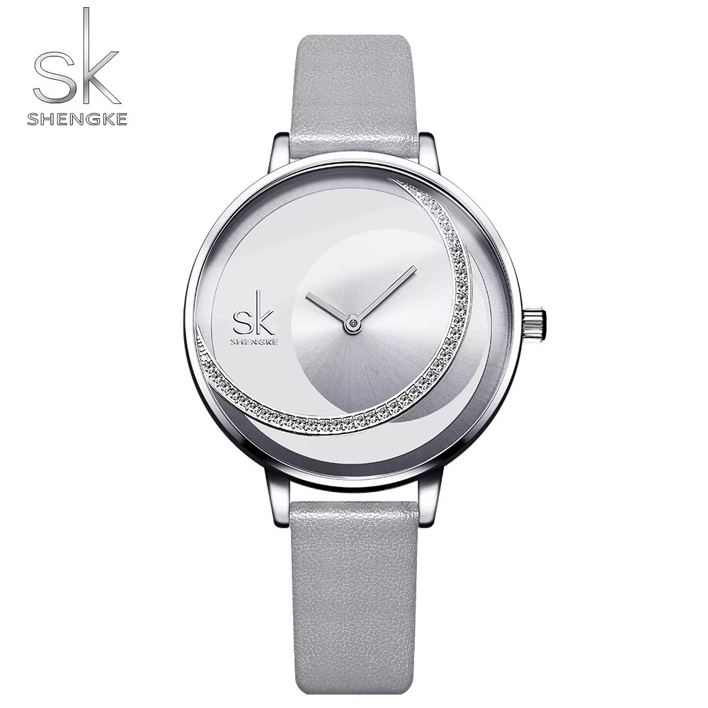Montre femme SHENGKE, cadran blanc orné d'un croissant de pierres scintillantes, boîtier argenté, bracelet gris